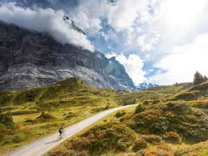Rennradfahrer auf der Strasse zur Grossen Scheidegg mit Blick auf das Wetterhorn und alpine Landschaft.