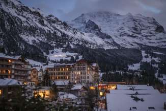 The village of Wengen in winter, blanketed in snow. A cloudy sky over the mountains.