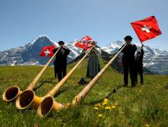 At the Mountain Spring Festival on the Männlichen, three musicians are playing the alphorn on the meadow.