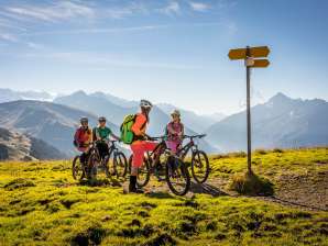 Die Biker schauen auf den Wegweiser und geniessen die Aussicht vom Hasliberg. Die Aussicht bietet einen sommerlichen Blick über die Berglandschaft.