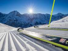 Skiers pose on the slope in Mürren-Schilthorn. The trio of the Eiger, Mönch, and Jungfrau can be seen in the distance.