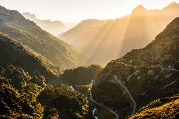 Die Passstrasse am Sustenpass verzweigt sich dur die mit Büschen überwachsene Felsenwelt. Die Sonneneinstralung am Abend verleiht der Landschaft eine romantische Stimmung.