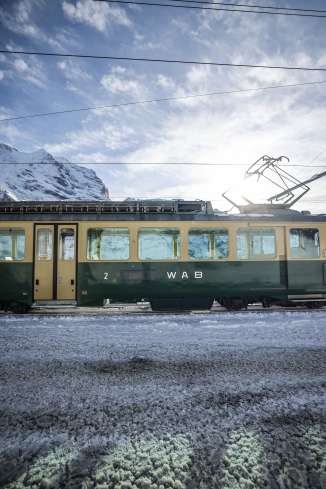 Dark green WAB in winter. Mountains can be seen behind the railroad tracks.