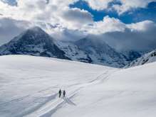 Winter hike on snow-covered trails around Grindelwald. Hikers enjoy the sunny day and the breathtaking view of the Eiger.