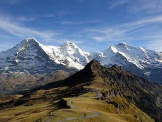 View of the summery Männlicher with the snow-capped trio of the Eiger, Mönch, and Jungfrau in the background.