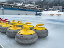Curling stones on the Wengen ice rink, with an ice resurfacer in the background.