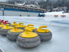 Curling stones on the Wengen ice rink, with an ice resurfacer in the background.