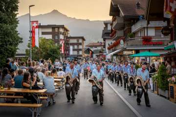 Traditional Trychler parade through the center of Grindelwald at dusk. Against the backdrop of the Bernese Alps, this Alpine custom becomes a memorable cultural experience.