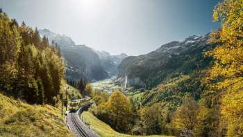 Die Wengernalpbahn unterwegs von Lauterbrunnen nach Wengen. Im Hintergrund das in Herbstfarben gehüllte Lauterbrunnental mit dem Staubbachfall.