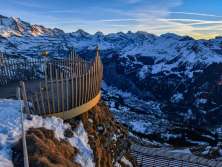 The crown of the Royal Walk is illuminated by the setting sun. The snow-covered mountain panorama in the background lends the region around Wengen a magical atmosphere.