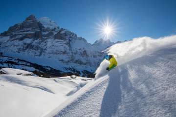 Skiing at the Grindelwald First ski resort. Skiers carve beautiful turns through the snow. In the background, you can see the Eiger.