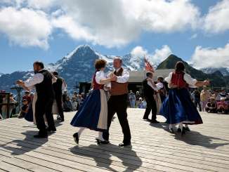 At the Mountain Spring Festival on the Männlichen, people dance in front of the panoramic view of the Eiger. The dancers are dressed in traditional costumes.