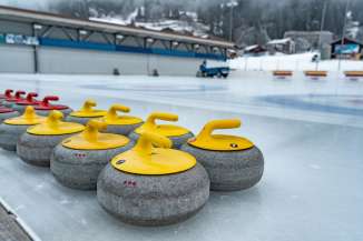 Curling stones on the Wengen ice rink, with an ice resurfacer in the background.