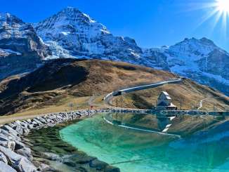 Lake Fallboden near Kleine Scheidegg is bathed in bright sunshine. In the background, the Eiger, Mönch, and Jungfrau rise up.