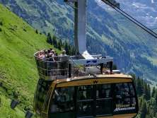 The Wengen–Männlichen cable car glides uphill over steep alpine meadows. In the background, the impressive high-mountain landscape rises up, highlighting the cable car’s spectacular setting.